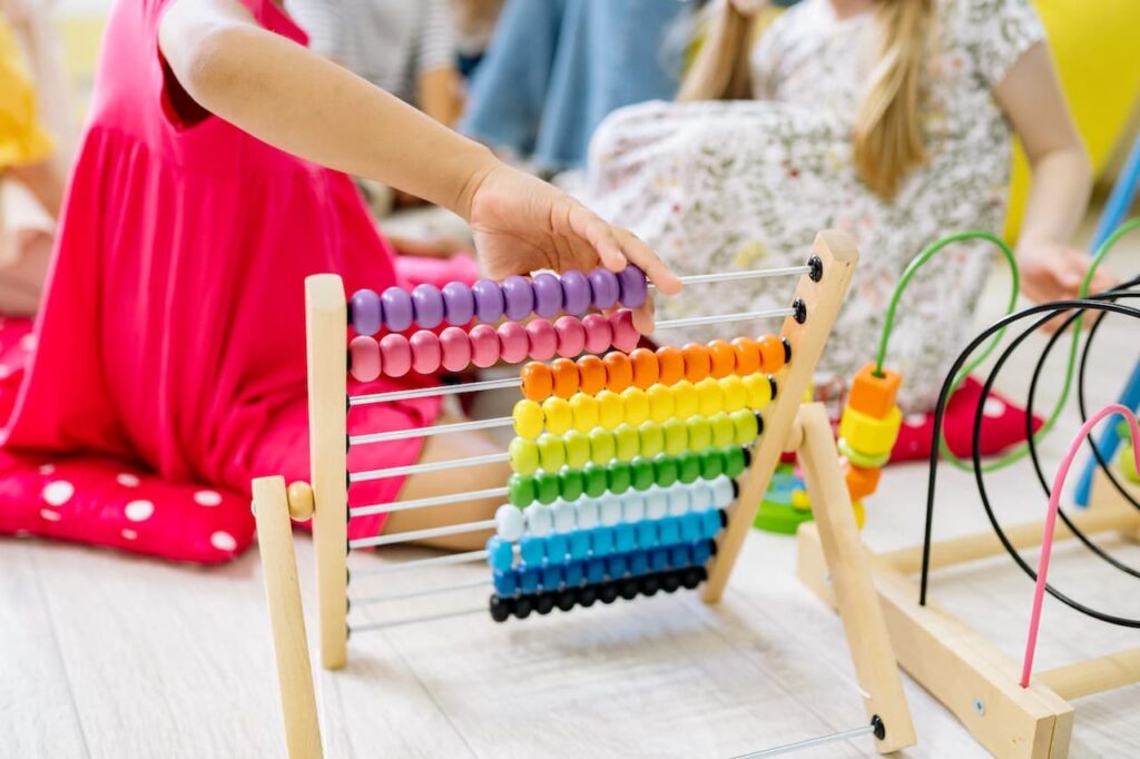 How to Teach Math to Preschoolers 3 A baby playing with a wooden abacus trying to learn maths