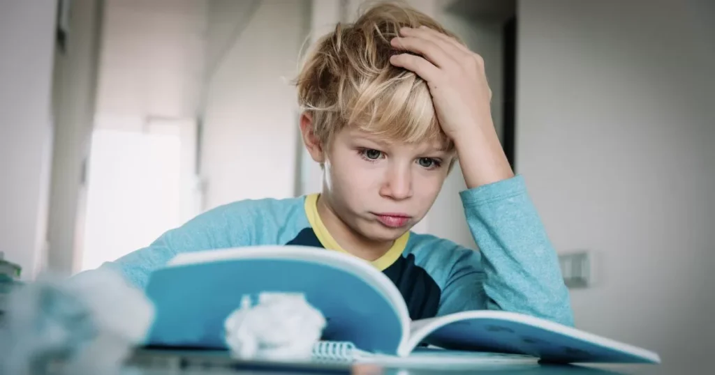 Effective Strategies To Improve Your kid's Reading Comprehension Skills 2 A young boy with a serious expression, holding his head while reading a book, appearing to struggle with understanding the content.